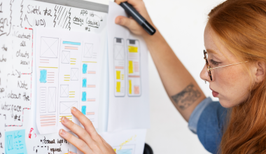 UX designer conducting an interview, showing a prototype to a user in a café to gather qualitative data.